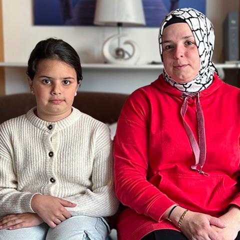 Mutter Gül sitzt mit ihren zwei Kindern im Wohnzimmer. Die Familie sucht eine neue und bezahlbare Wohnung.